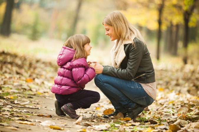 Mother and daughter having fun in park in autumn